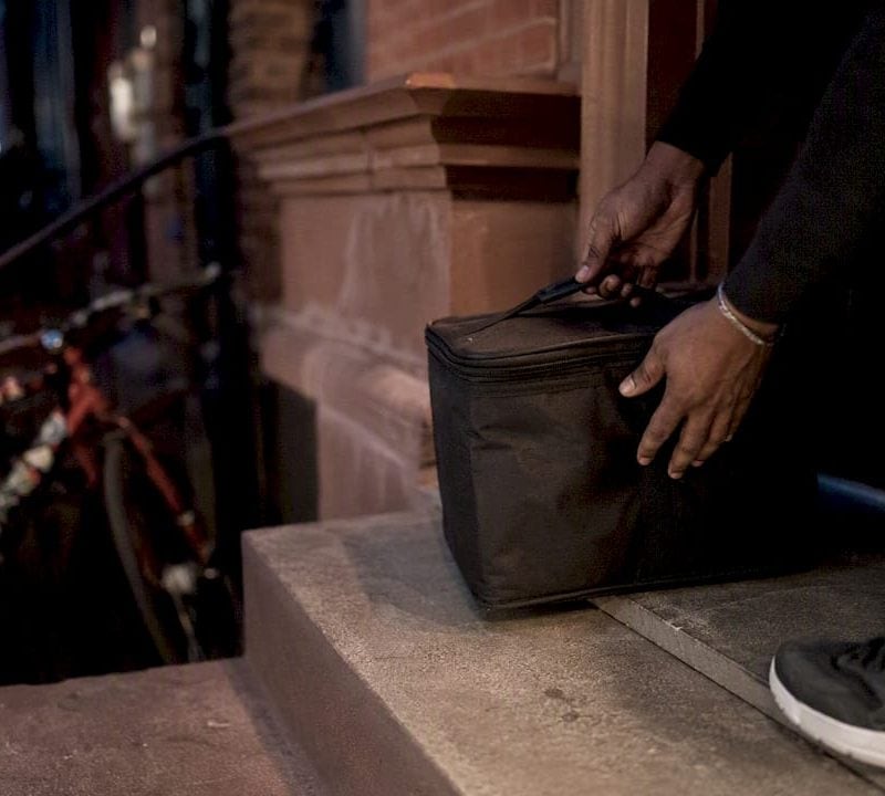 Hands placing cannabis delivery bag on NYC doorstep