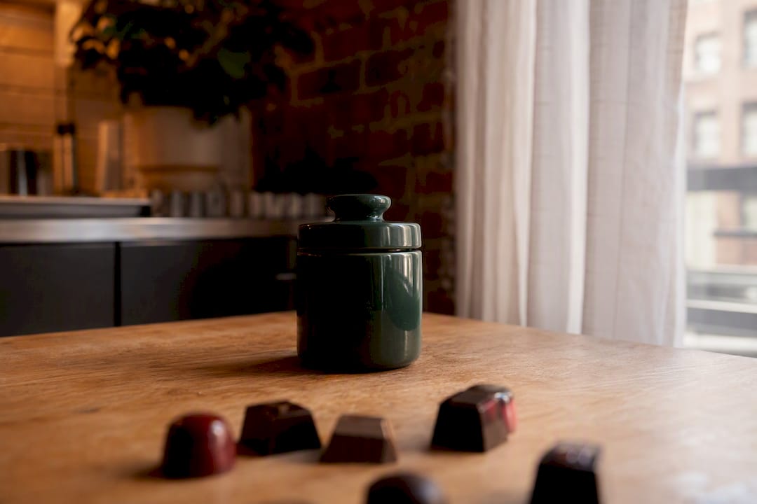 Tinted jar blocking light on dark table with gummies