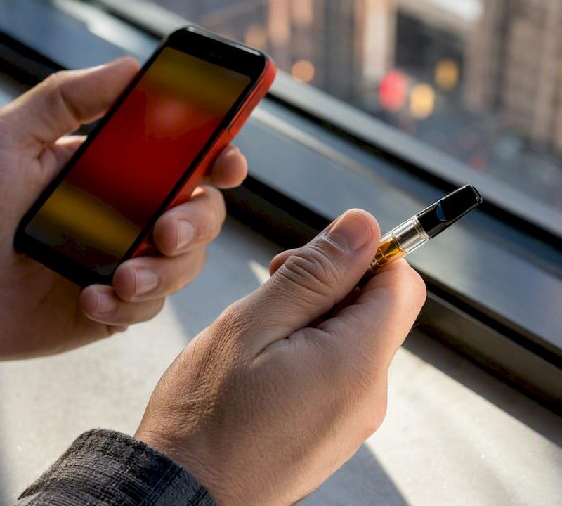 Hands checking anonymous vape cartridge by phone