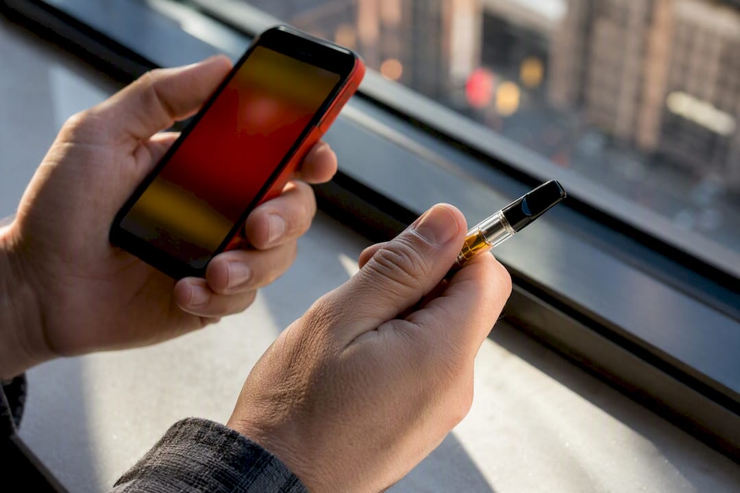 Hands checking anonymous vape cartridge by phone