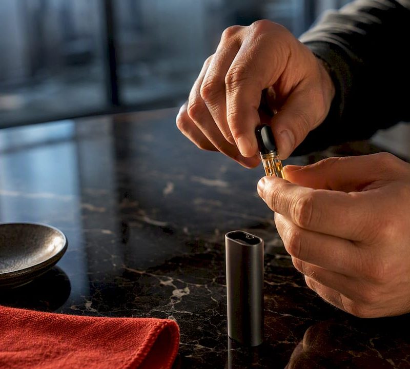 Hands gently warming a clogged vape cartridge