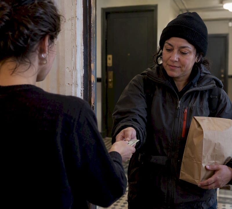 Customer hands a cash tip to delivery driver